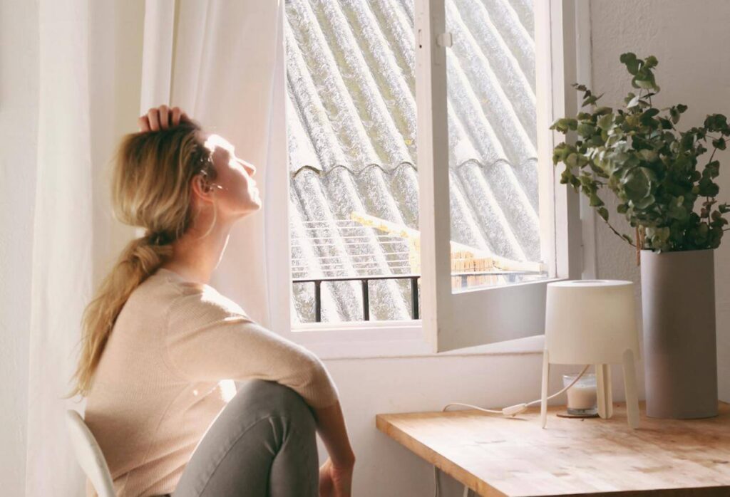 #28 FamilyShift Beitragsbild: Ruhige Frau sitzt vor offenem Fenster