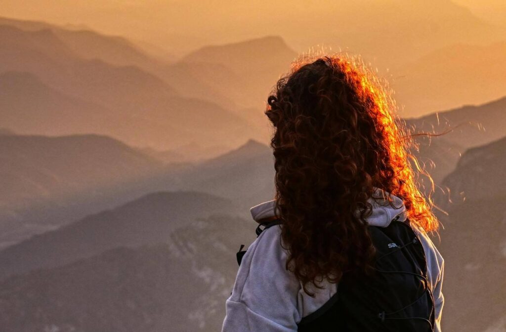 #32 FamilyShift Beitragsbild: Frau steht im Sonnenuntergang auf dem Berg