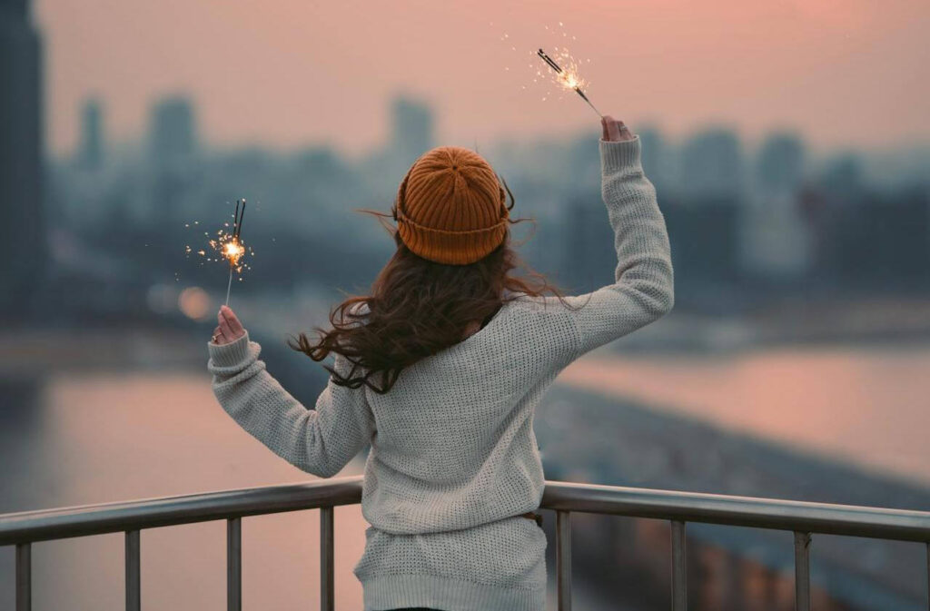 #93 ziemlichglücklich: eine Frau steht mit Wunderkerzen vor einer Skyline