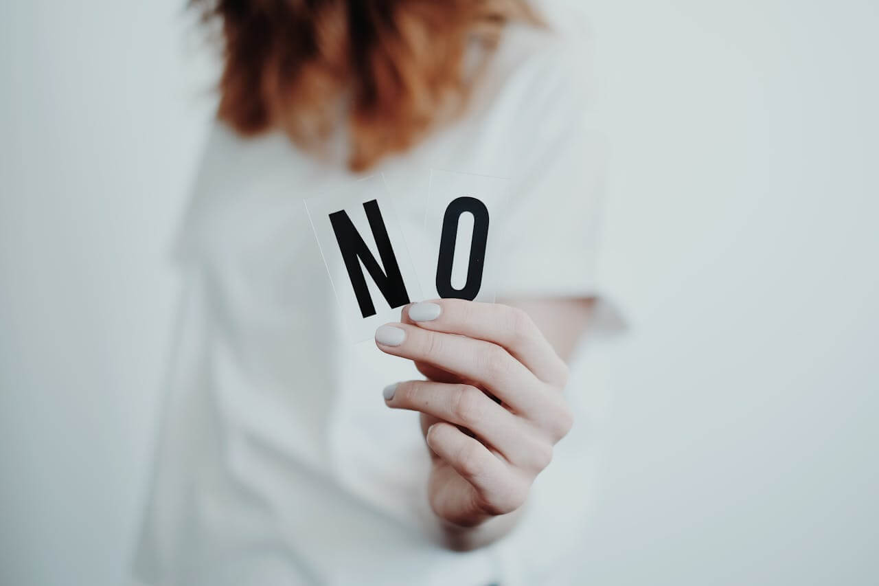 #106 ziemlichglücklich Beitragsbild: Eine Frau hält das Wort "NO" in die Kamera